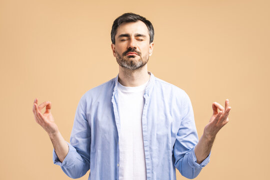 Portrait of handsome bearded man meditating isolated on beige background