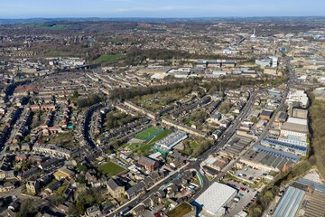 Fototapeta premium Aerial view of the town of Huddersfield in West Yorkshire showing suburban housing green spaces and a football pitch with town centre and countryside stretching into the distance in the spring time