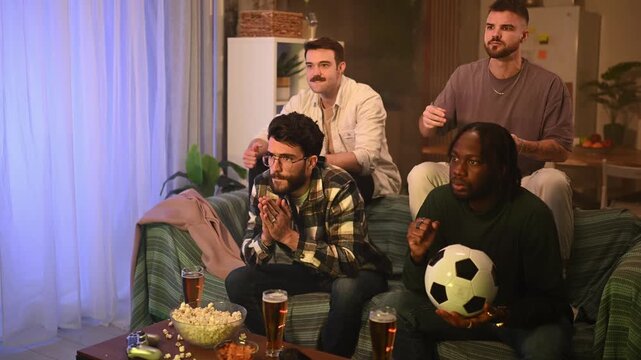 Multiethnic friends watching a soccer game on tv exploding with joy and celebrating a victory goal together at home