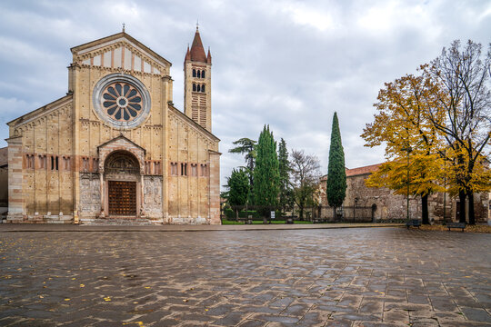 Facade of San Zeno Maggiore Basilica and square with wet pavement, Verona.