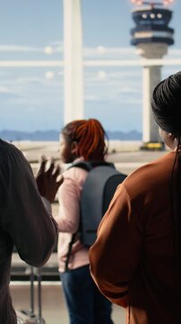 Vertical Video Sad yet proud parents waving goodbye during emotional send-off with their child at the airport. Teenager walking toward gate for boarding, international flight for university abroad