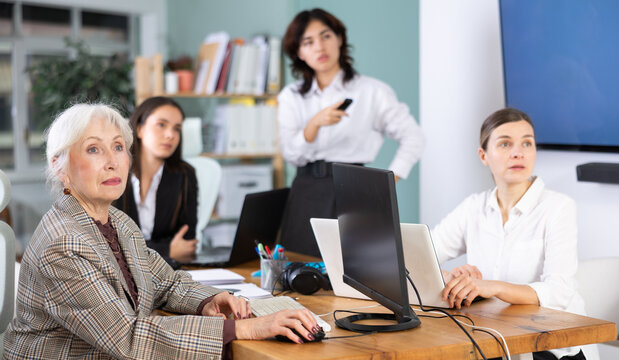 Focused female colleagues watching a project demonstration and working on computers in modern office