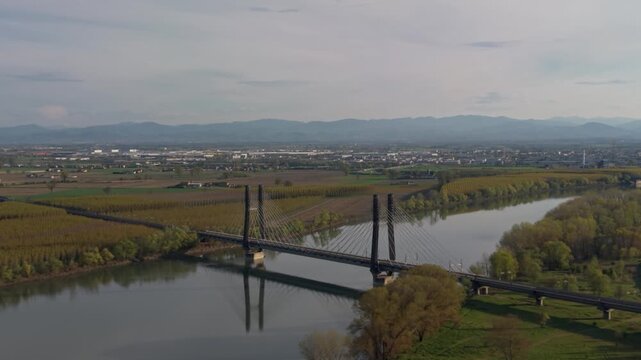 Drone aerial view of cable stayed railway bridge crossing Po River in Italy. High speed rail infrastructure connecting major cities with modern engineering design.