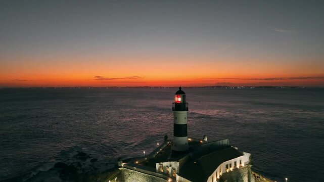 Farol da Barra lighthouse beneath intense red sunset sky with glowing horizon over the Atlantic Ocean in Salvador, Bahia, Brazil