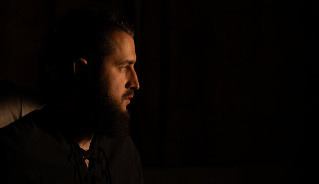 beard man profile face portrait dark hair dramatic mysterious atmosphere black background empty copy space