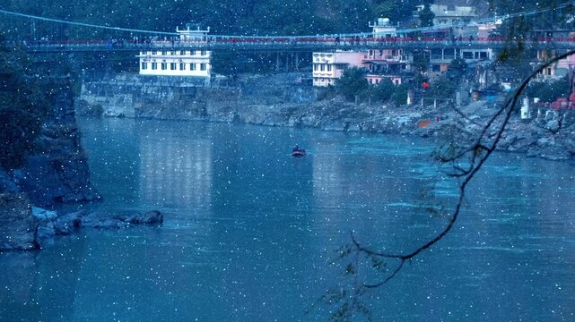 Rafting on an inflatable boat is sailing on the holy waters of The Great River Ganga (Ganges) passing under the famous Ram Jhula bridge in Rishikesh, Uttarakhand, India. View through sparkling particl