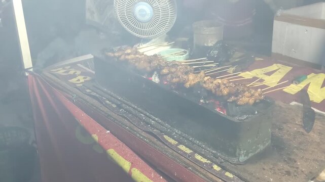 Grilling Skewered Meat Over Hot Coals with Smoke Rising Traditional Street Food Preparation. 4k Footage Video