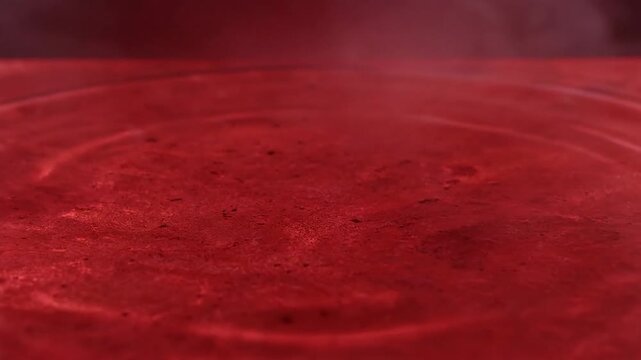 A single drop of red liquid creates ripples on a vibrant crimson surface showcasing fluid dynamics and surface tension.