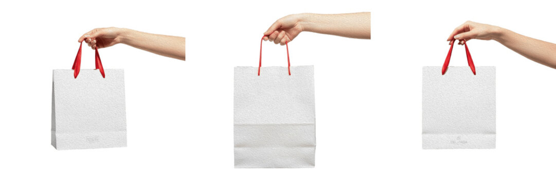 Set of hands holding a white paper shopping bag with red handles, mockup concept for retail branding, fashion boutique, and gift delivery on a white background.