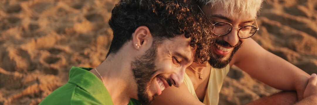 Romantic moments, homosexual couple enjoying intercourse with each other while sitting on the beach at dawn. Panoramic