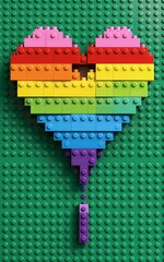 Obraz premium Rainbow LEGO heart on green baseplate colorful and playful.