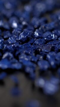 Super slow motion, Closeup Of Blue Pebbles Slowly Moving On Dark Slate With Polished Reflections