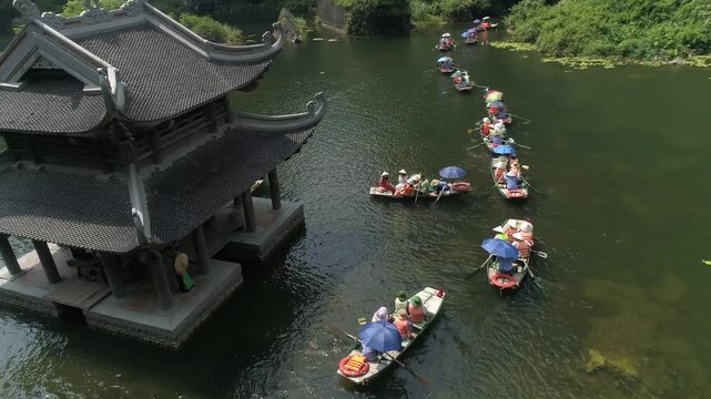 Serene river landscape with small boats passing through the majestic limestone karsts of Tam Coc, Vietnam