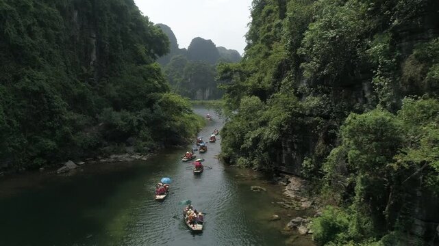 Aerial view of small rowing boats traveling on a scenic river between limestone mountains in Ninh Binh, Vietnam
