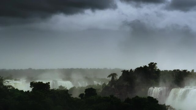 Iguazu Falls (Cataratas del Iguaz&uacute;) in misty rainforest under dramatic storm clouds