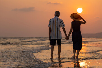 Silhouette  of Asian senior couple enjoying their vacation watching at the sunset sea beach in...
