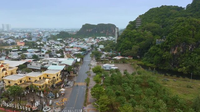Aerial view of Da Nang, Vietnam, showcasing the city's blend of urban and natural landscapes. Focus on the road leading to the Marble Mountains and pagoda.