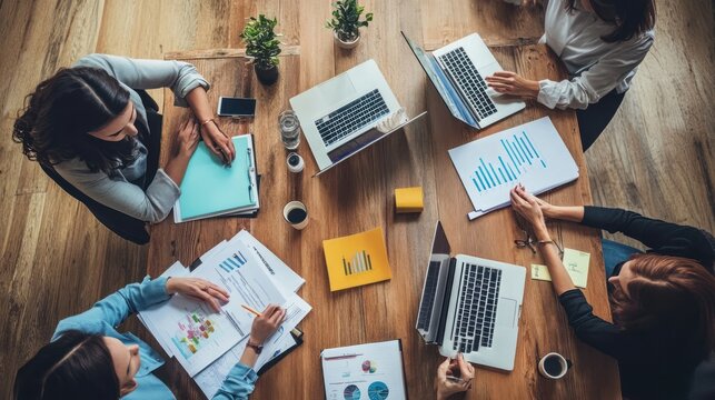 Collaborative Business Meeting: Diverse Women Analyzing Data on Wooden Table, Top View