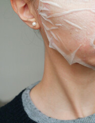 Fototapeta premium close up of the lower face and neck of a young caucasian woman doing a sheet face mask