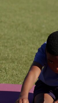 Warmup starting boy holding toes, camera panning showing girl mirroring stretch on mats for fitness
