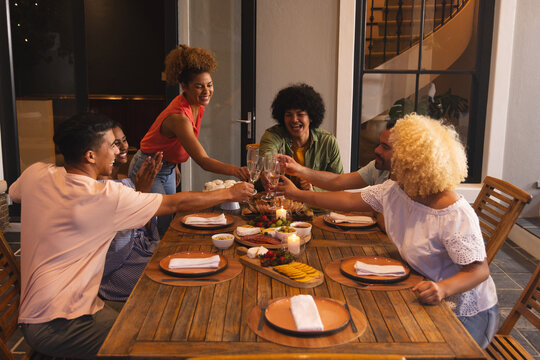 Host starting toast, group raising wine glasses and clinking over cheese board, celebrating food