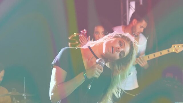 Camera rising showing female singer stepping, bringing mic, singing, flipping hair on concert stage