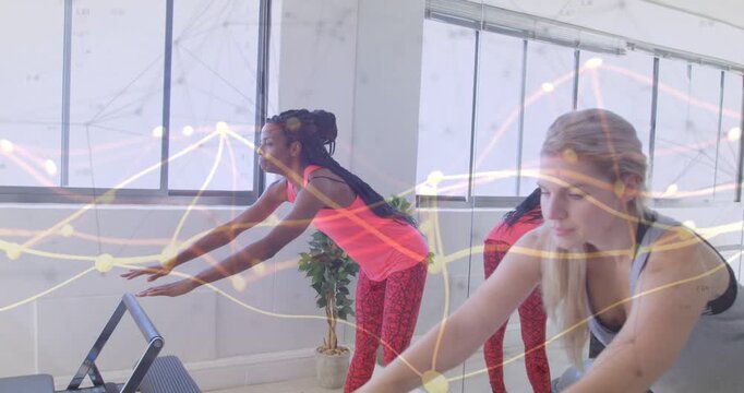 Two women stepping to reformer, hinging and holding for pilates pose light lines overlaying scene