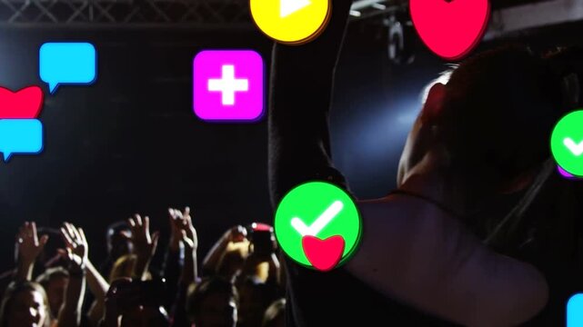 Cheering fans urging singer onstage in dark top raising arm, swinging hair, singing into mic, icons