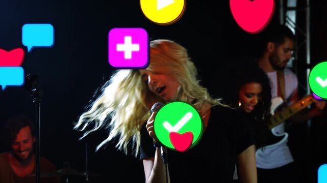 Lead singer singing holding wired mic, bassist playing bass, music causing app icons layering over