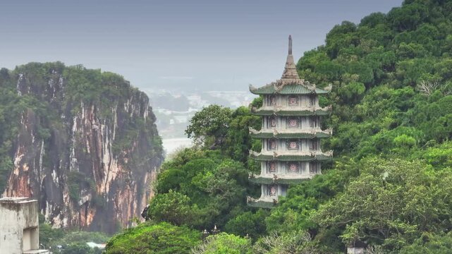 A scenic view of the Marble Mountains featuring the Xa Loi Tower, a pagoda, surrounded by lush greenery in Da Nang, Vietnam. It's a popular tourist destination.