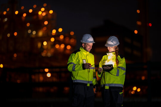 Engineers working night shift at industrial plant with tablet