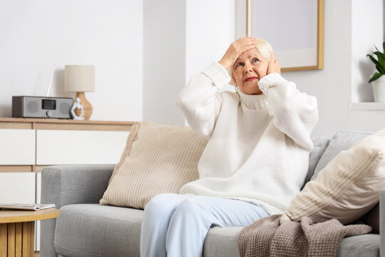 Senior woman on sofa suffering from loud neighbours at home