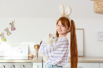 Cute girl with adorable cat and bunny ears in festive kitchen. Easter celebration © Pixel-Shot