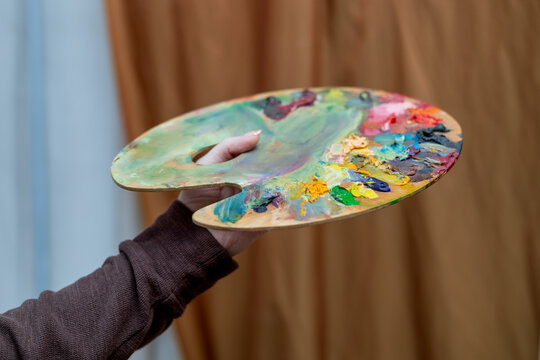  A palette of oil paints in an artist's hand. Photo from a creative studio. 