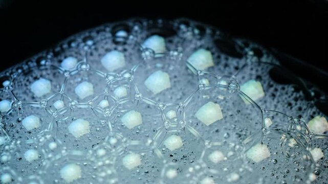 Close-up view of soap bubbles and salt crystals against dark background