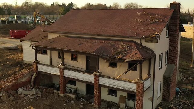 Aerial view of damaged residential house at construction site in Wisconsin. Old building with visible roof damage prepared for renovation, demolition or redevelopment.