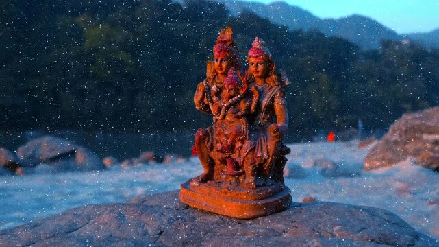 Shiva Parivar statue, depicting the Hindu deity Lord Shiva with his consort Goddess Parvati and their son Lord Ganesha is placed on the rock on the bank of the holy Great Ganga (Ganges) river 