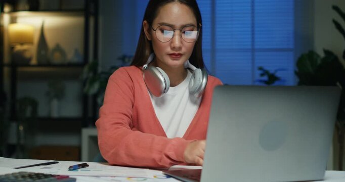 An Asian person plans individual revenue goals and tax deductions, calculating finances with emotion on a late-night setup.