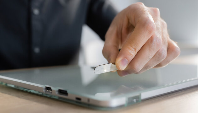 Closeup of a person inserting a USB flash drive into a laptop computer.