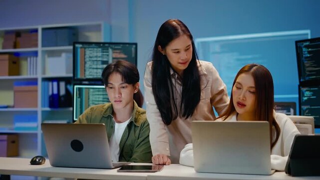 Asian business team of programmer working and Ai coding in night office.Professional software engineer training and collaborate on project script with laptop.Concept of Ai agent,digital tech startup