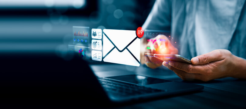 Business professional holding smartphone with email envelope notification and digital marketing dashboard, representing online communication, messaging system, data analytics, business interaction