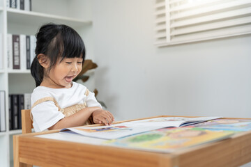 Naklejka premium Happy Asian children relax read book at home. daughter and reading a story. learn development, childcare, laughing, education, storytelling, practice, imagine, reduce addiction mobile pho