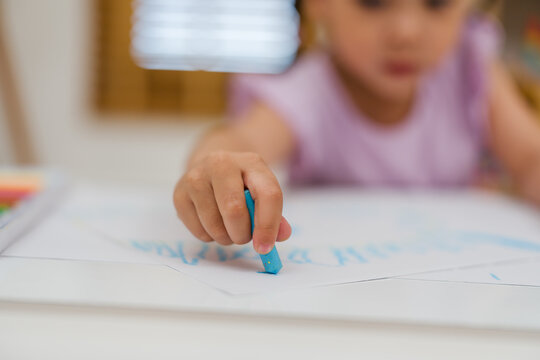 close up preschool child girl drawing and painting with colorful oil pastels on paper