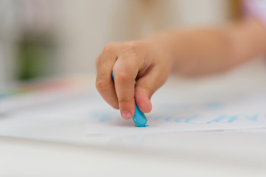 close up preschool child girl drawing and painting with colorful oil pastels on paper