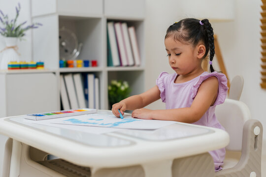 preschool child girl drawing and painting with colorful oil pastels on paper