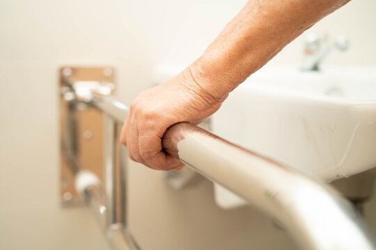 Asian elderly woman use safety handrail in bathroom.