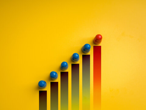 Blue human figures on rising bar chart with red leader on top, symbolizing leadership, population growth, progress, human development, social dynamics, and team management on yellow background.