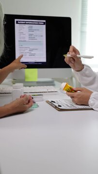 Young female doctor giving medical advice and explaining prescription drug dosage to an elderly woman during a checkup.