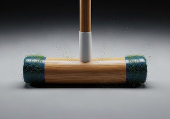 Obraz premium Close-up of a vintage croquet mallet ready to strike a ball on a grey surface.