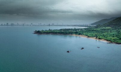Fototapeta premium An aerial view of Da Nang, Vietnam, showcasing the city's coastline and skyline on a cloudy day. The image captures the blend of urban and natural landscapes.